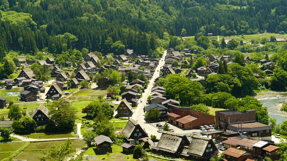 A stunning aerial view of Shirakawa-go, Gifu, Japan, showcasing traditional gassho-style houses surrounded by lush greenery.