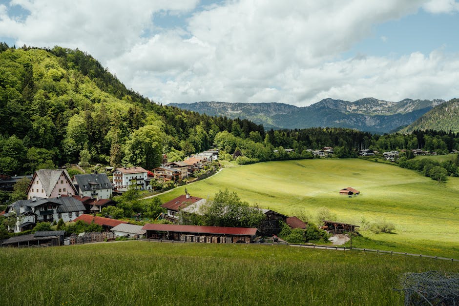 Idyllic rural landscape with lush green hills, mountains, and a charming village.